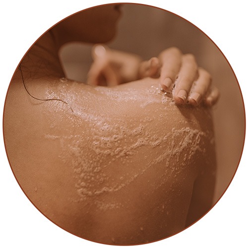 Woman exfoliating her shoulder | All in Custom Spray Tanning